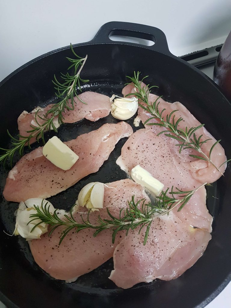 Chicken breast cooking in cast iron skillet